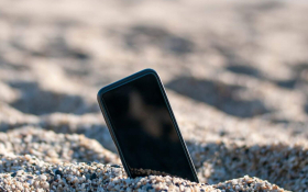 A smartphone sticking out of the sand at the beach