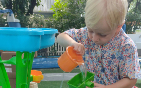 A white toddler playing with water toys