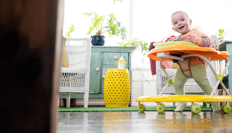 A white baby using a baby walker on wheels