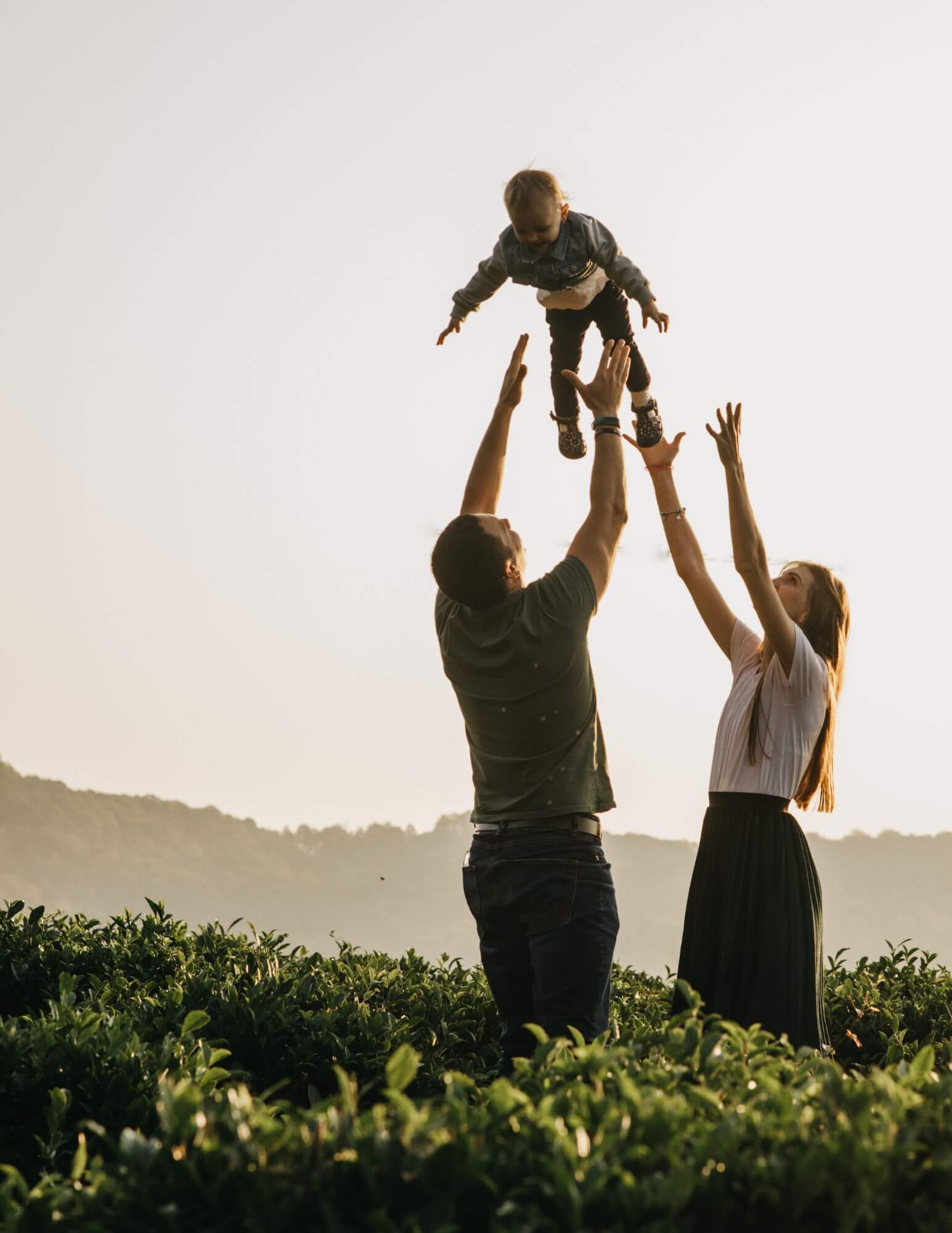 A mother and father playing and throwing their toddler in the air