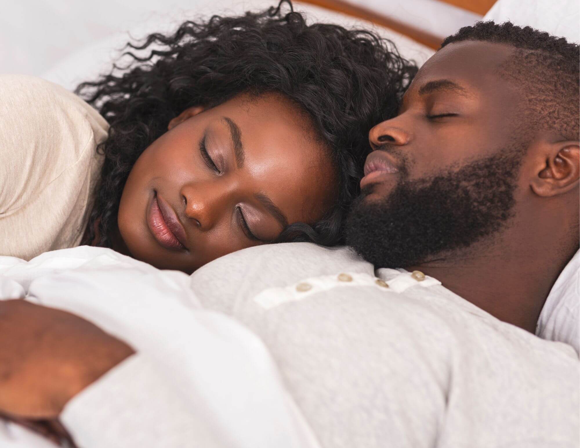 A Black man and woman - a couple - lying together and sleeping