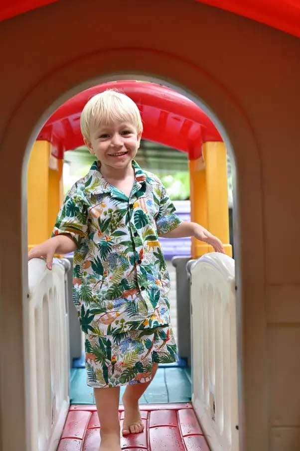 A white toddler boy smiling at the camera while on a play structure