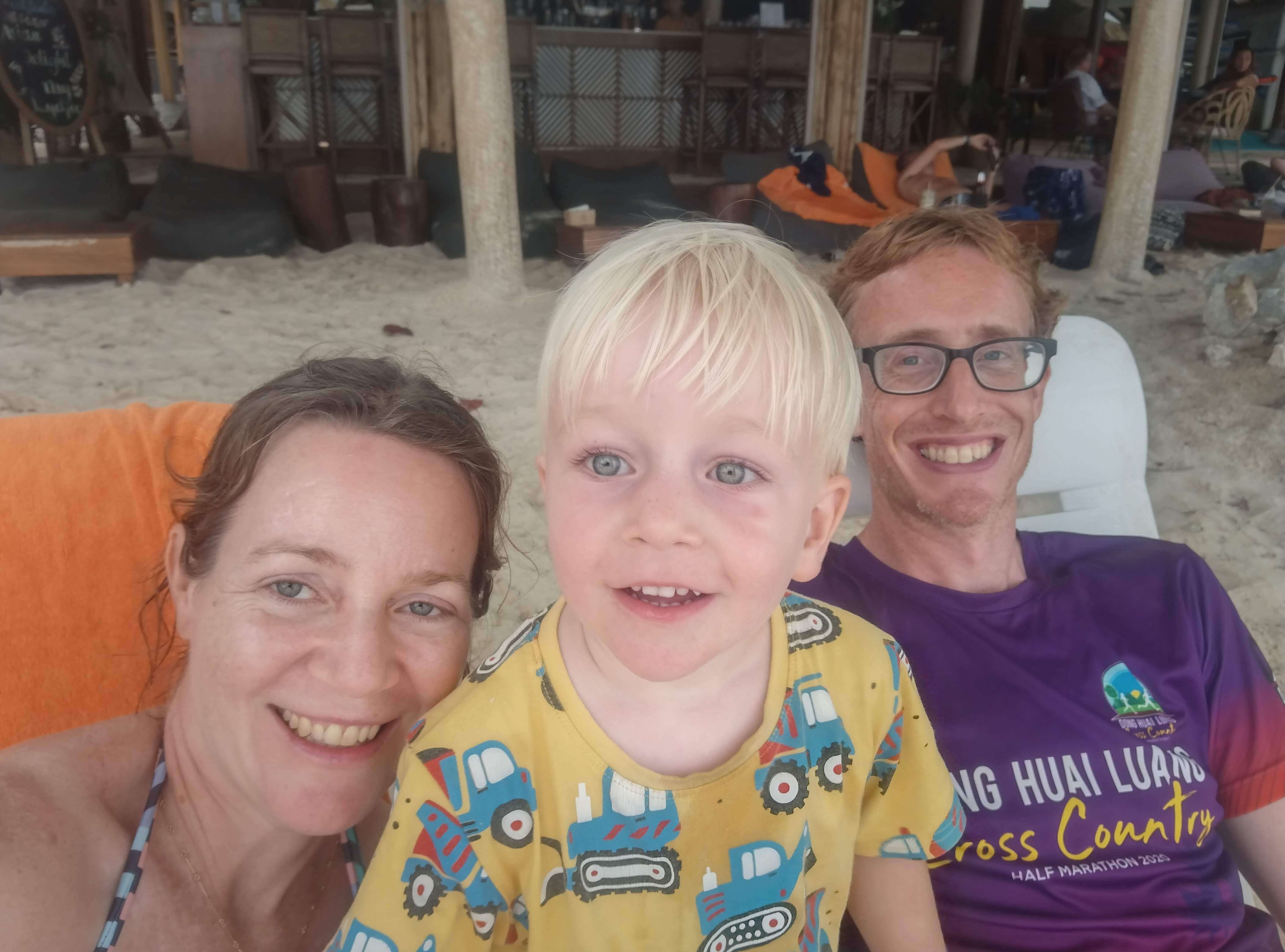 A white family of three - mother, father, and son - smiling at the camera