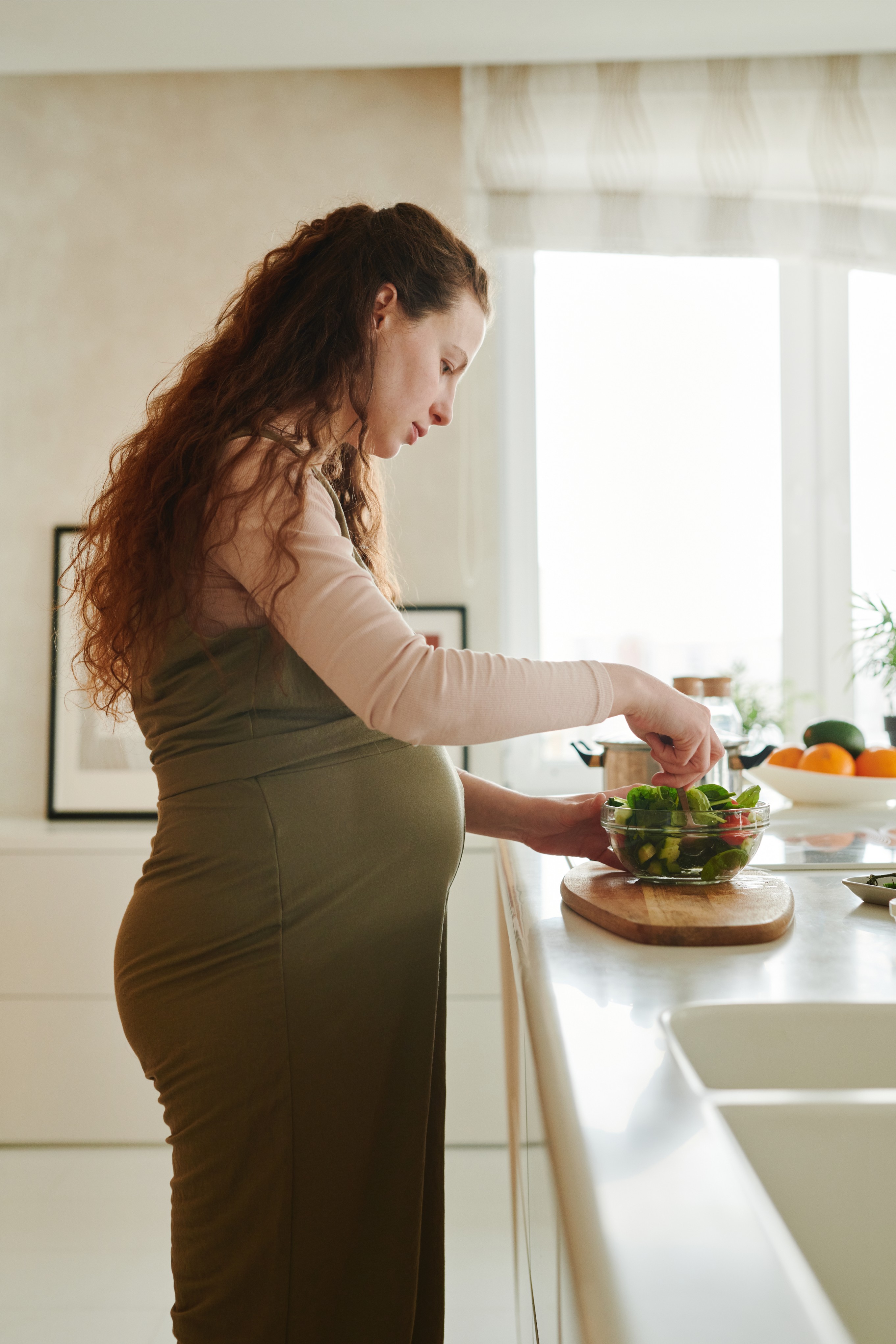 A pregnant woman mixes a salad