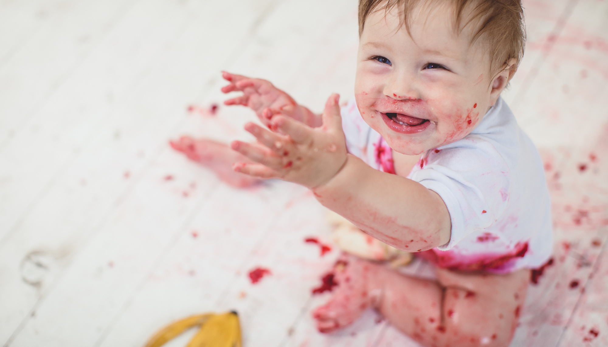 White baby with food stains on clothes reaching out 
