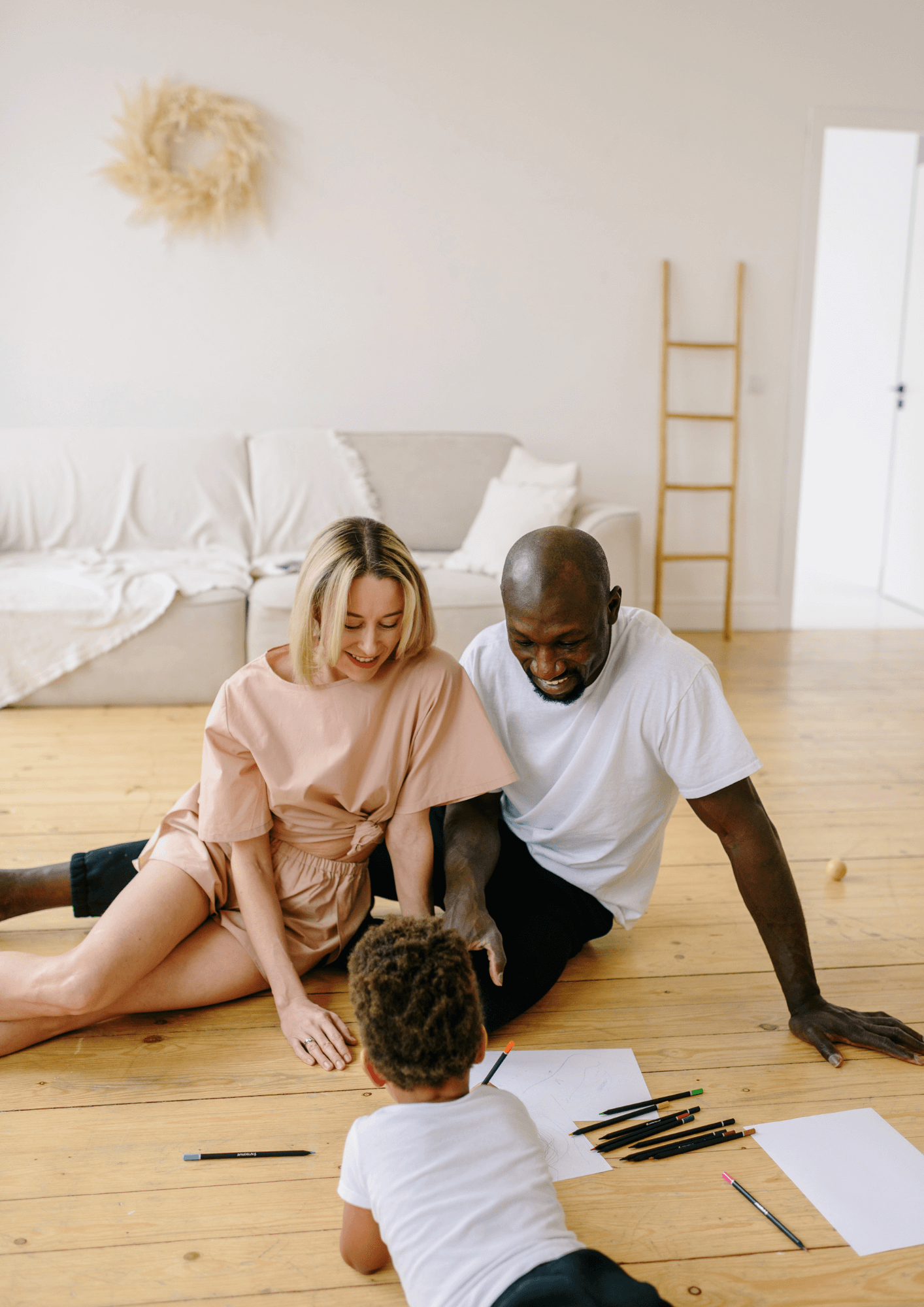 A couple sit on the floor facing their child