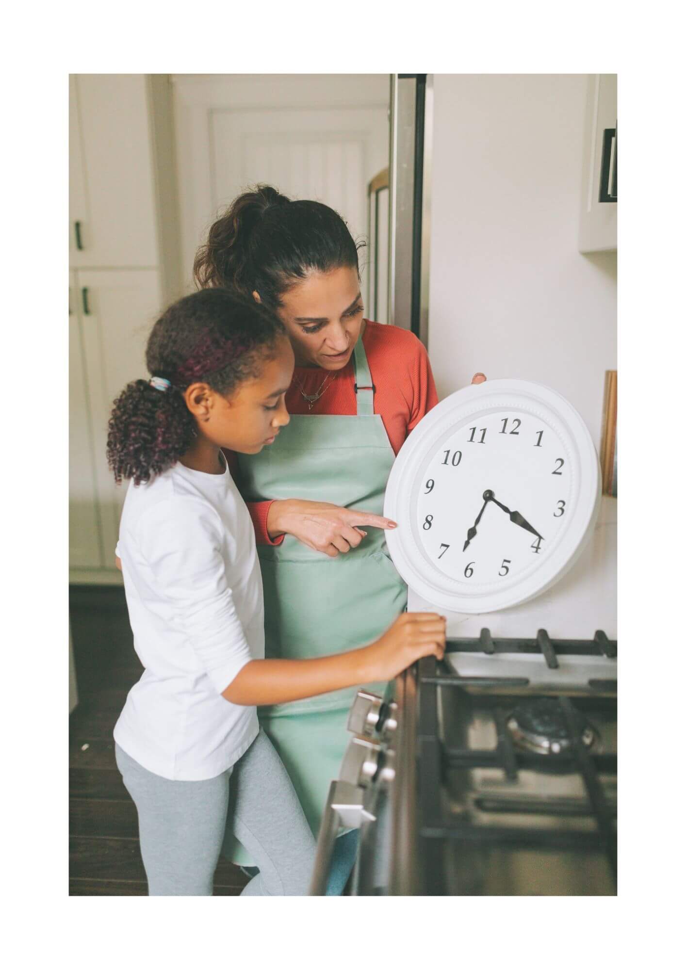 A woman showing a girl how to read an analog clock