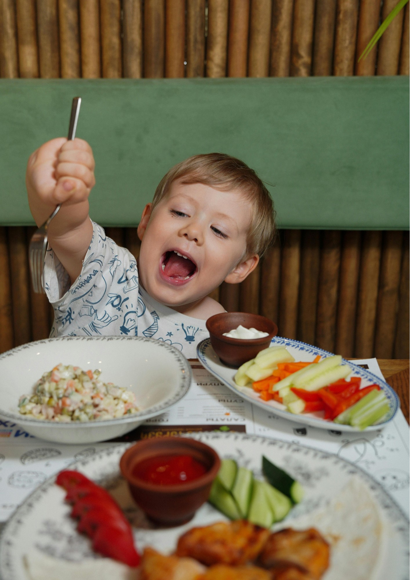 A smiling boy sits at a full table