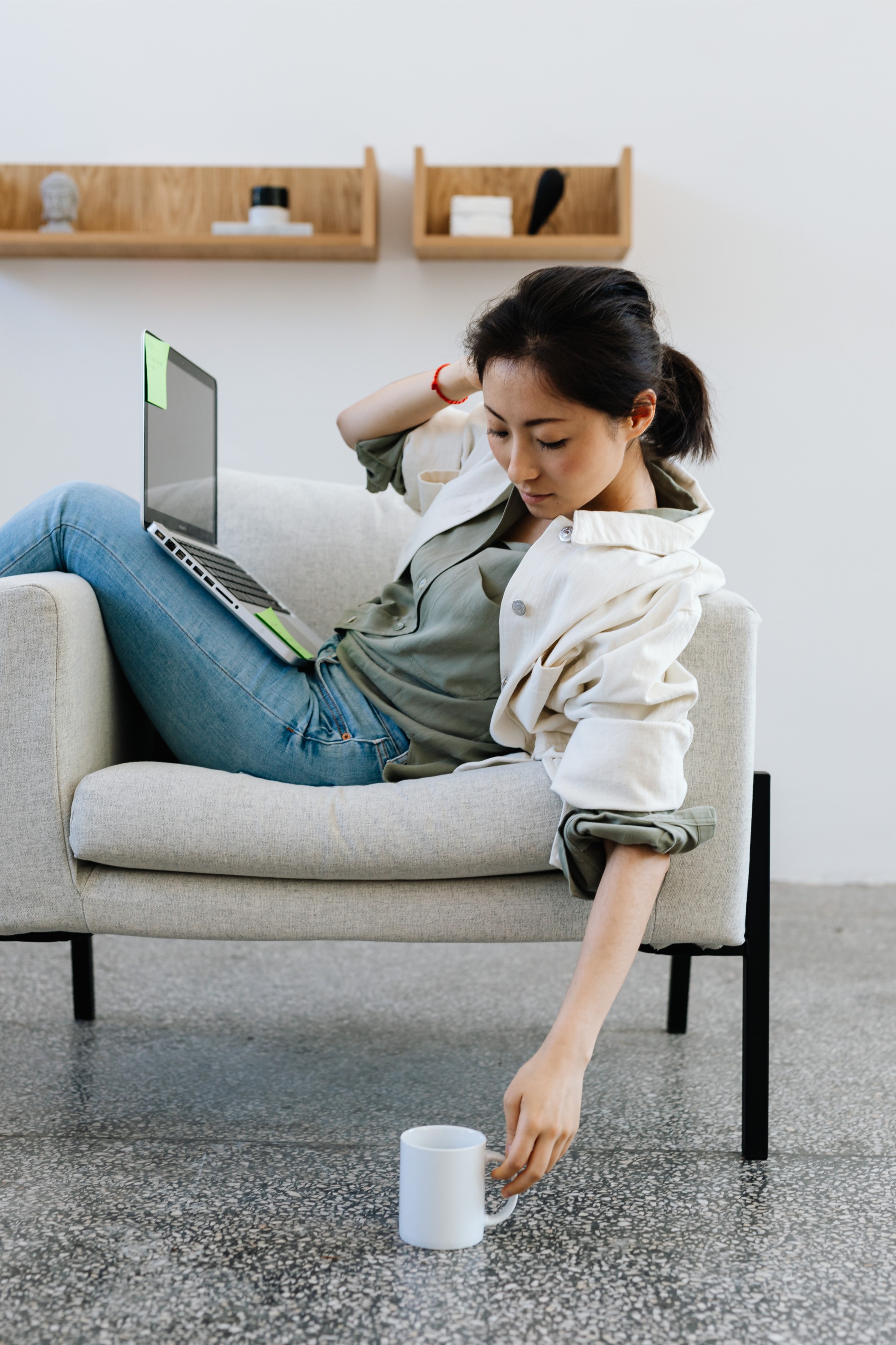 A lady slouches across a chair with a laptop