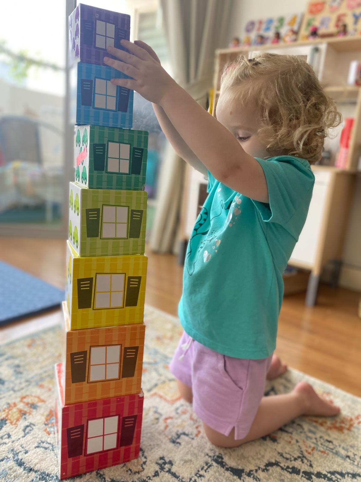 A White toddler playing with nesting toys