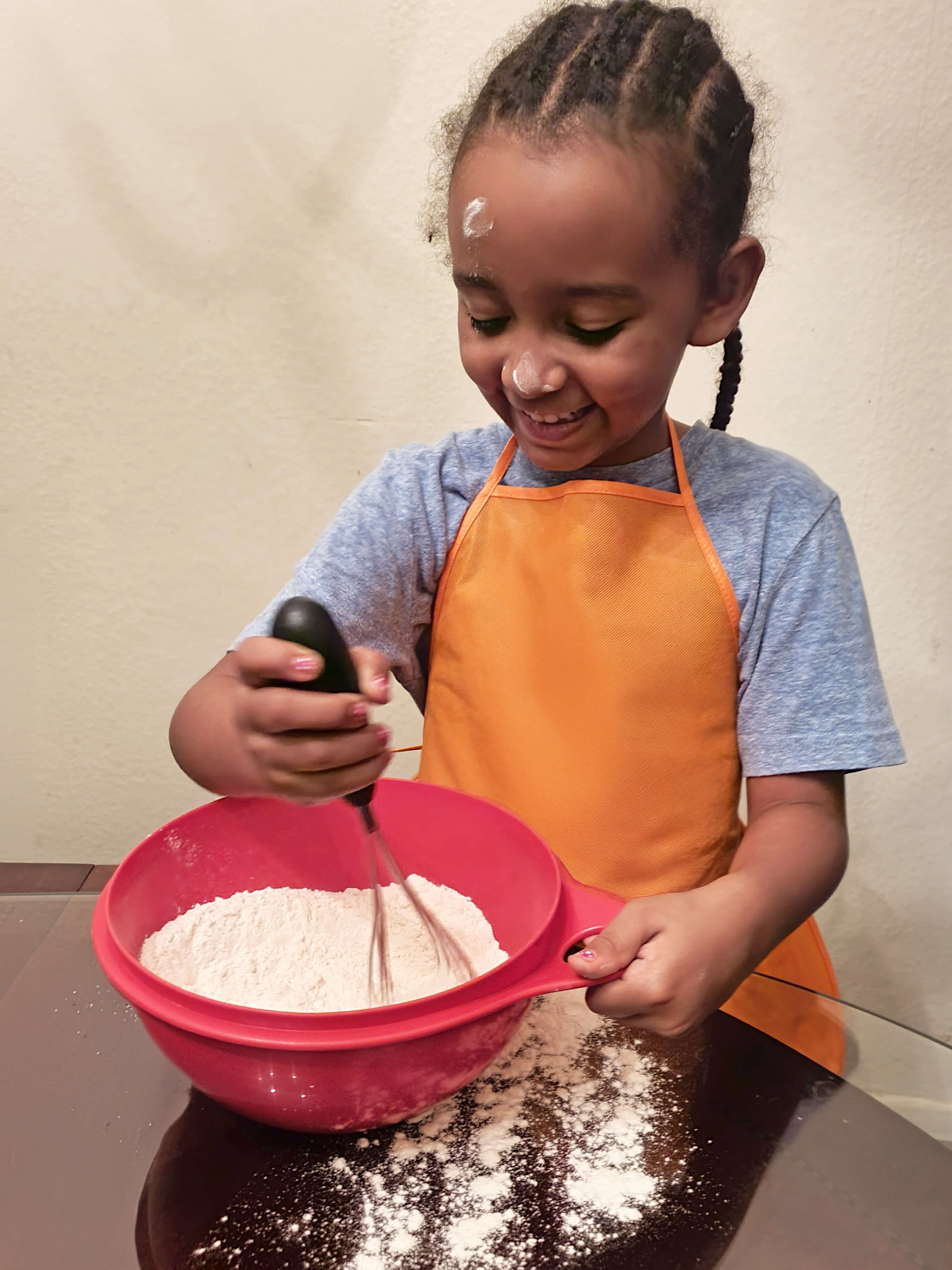 A girl stirs a bowl of flour