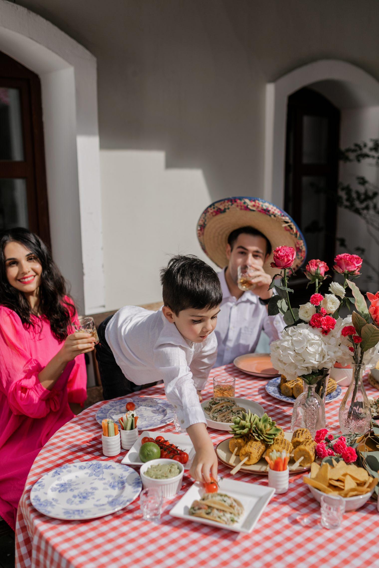 A boy at a party reaches across the dinner table