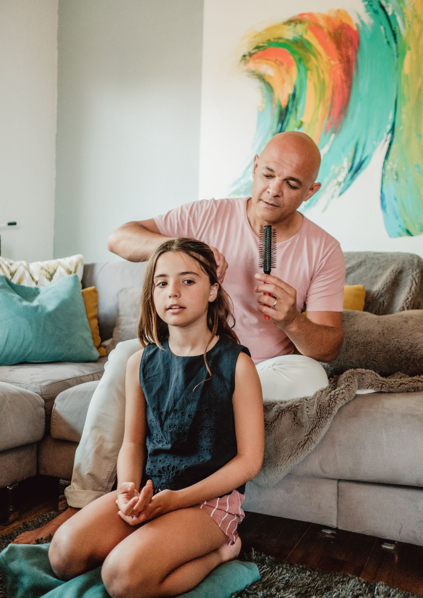 A father combs his daughter's hair.