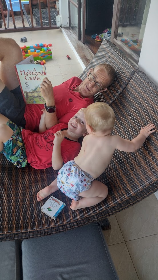 A father and two children lie on a deckchair.
