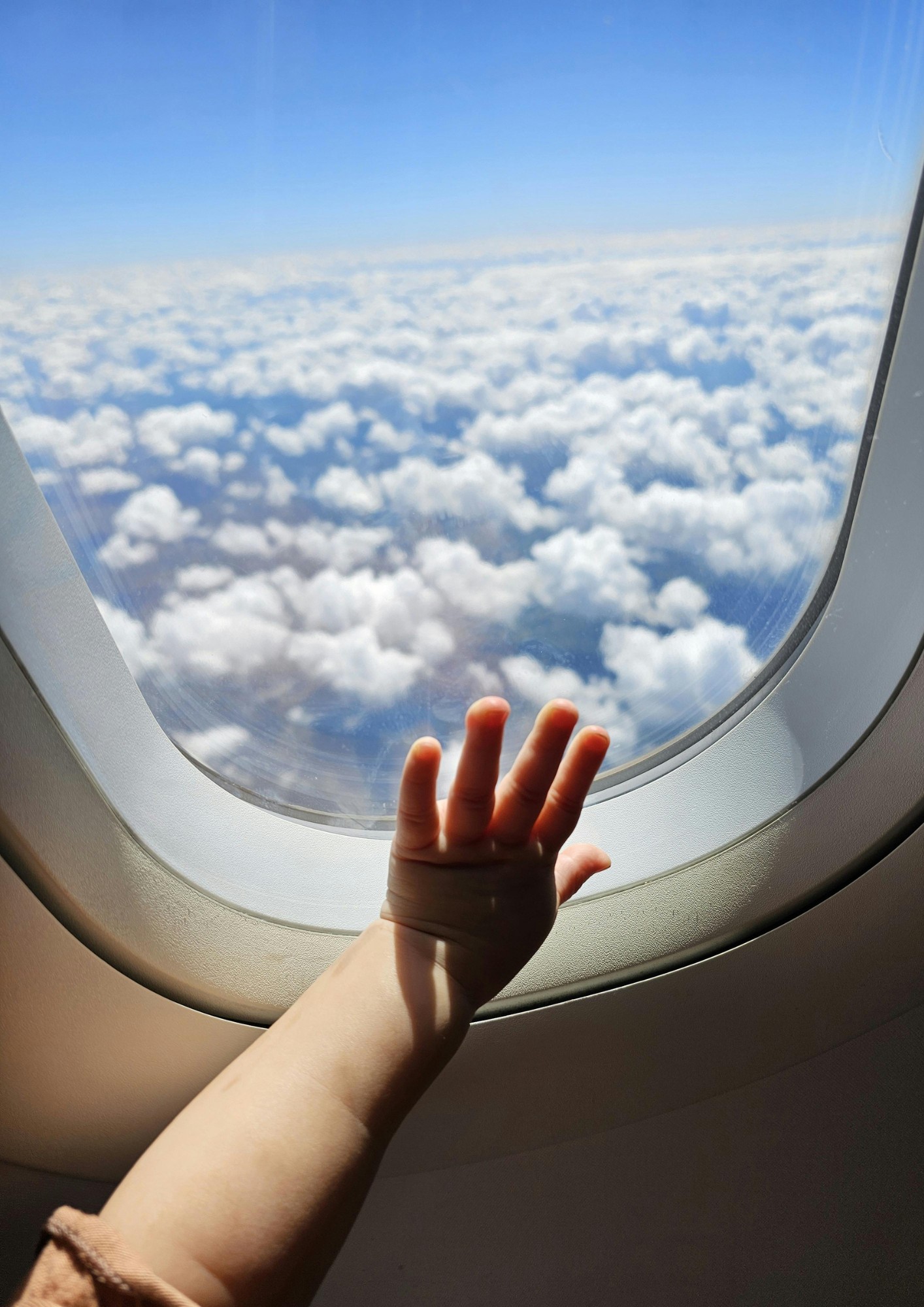 A child presses their hand to an airplane window