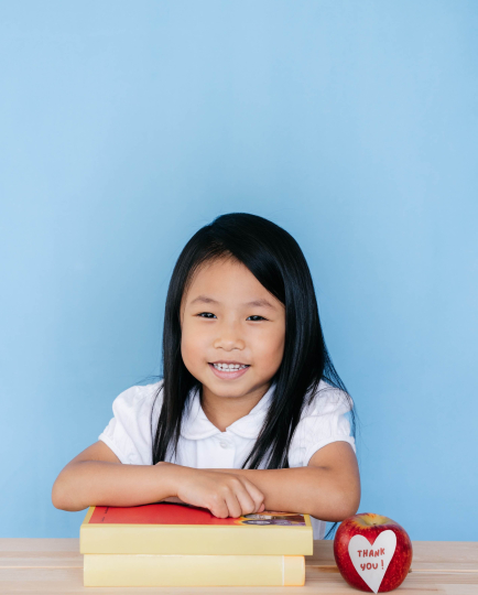 A girl leans on a pile of books.