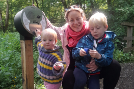 A mother and children crouch by a sign 