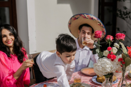 A boy at a party reaches across the dinner table