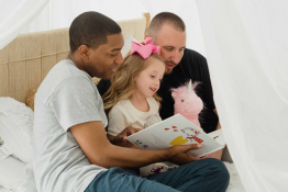 Two parents read to their daughter