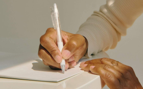 A person's hands writing notes in a notebook