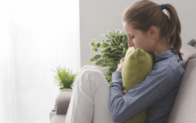 A white woman sitting on the sofa and hugging a pillow