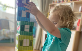 A white toddler playing with nesting blocks