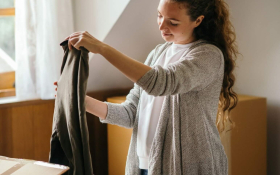 A White woman packing clothes into a moving box