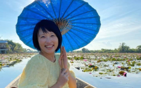 A Chinese woman sitting in a boat on a lotus pond and smiling