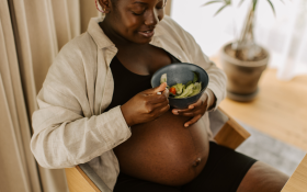 A Black pregnant woman eating vegetables