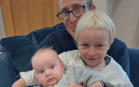 Two children sit on their father.