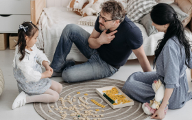 A family sit together on the floor.