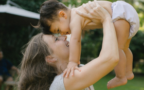 A mother lifts her child above her head.