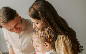 A family of three stand together.