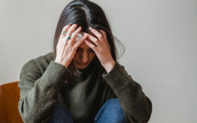 A lady crouches head in hands.