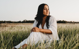 A lady in white sits in a field