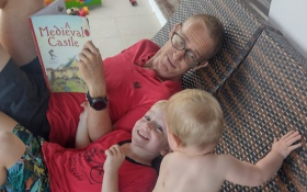 A father and two children lie on a deckchair.