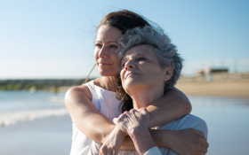 A lady hugs her mother on a beach
