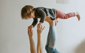 A child balances on their mother's legs