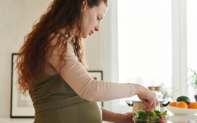 A pregnant woman makes a salad