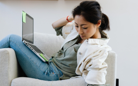  A lady slouches over an armchair with a laptop