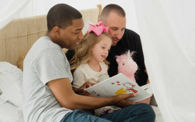 Two parents read to their daughter