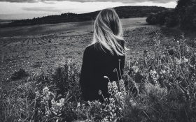 A black and white lady stands in a field