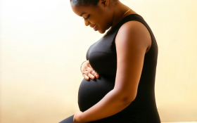 A pregnant women sits holding her tummy